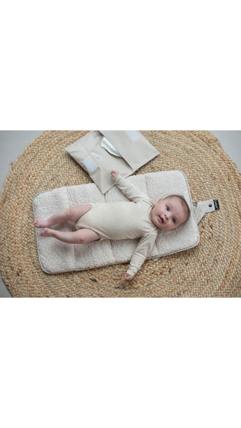 Smiling baby lying on soft portable changing mat with diaper pouch