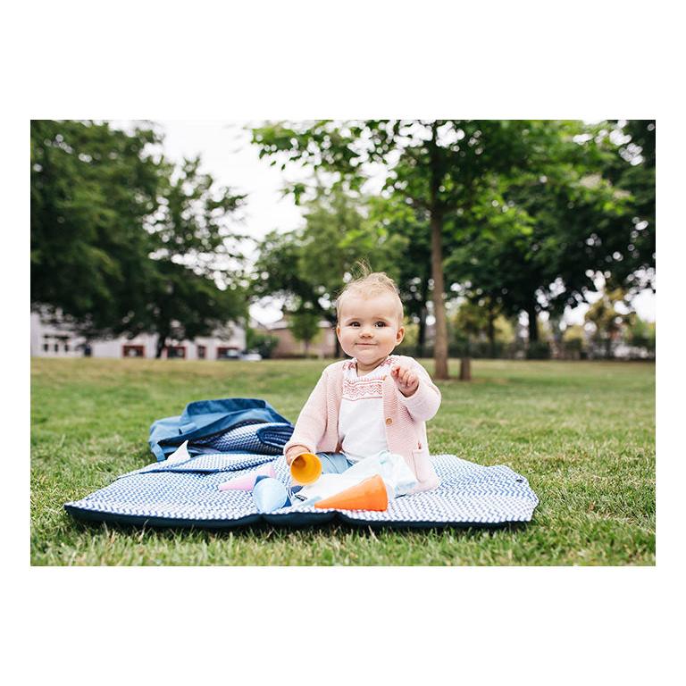 Baby sitting on play mat with toys outdoors